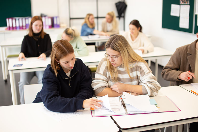 Zwei Auszubildende in Freizeitkleidung bearbeiten im Klassenraum eine Aufgabe